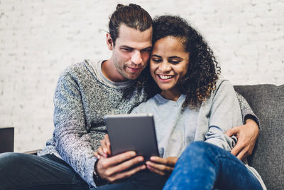 Smiling couple watching movie over digital tablet at home