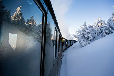 Train by snow covered land against sky