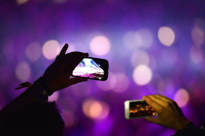 Close-up of hand holding smart phone at music concert