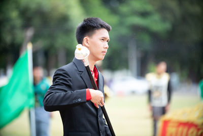 Young man looking away while holding pole