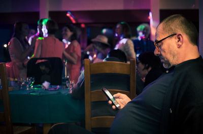 Side view of man using phone in party