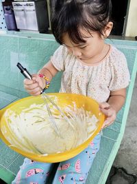 High angle view of girl mixing food in bowl at home