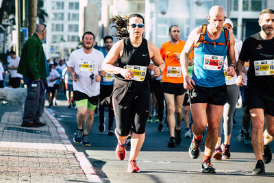 Group of people running on street in city