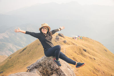 Portrait of man with arms outstretched against mountain range