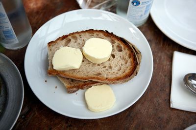 High angle view of bread and butter served in plate on wooden table