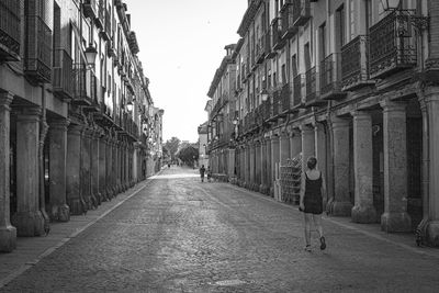 Rear view of man walking on street amidst buildings