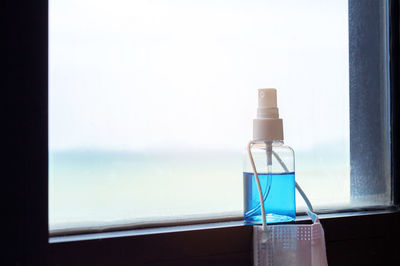 Close-up of glass bottle on table by sea against sky