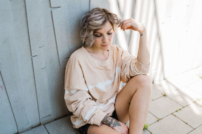 High angle view of woman sitting by wall outdoors