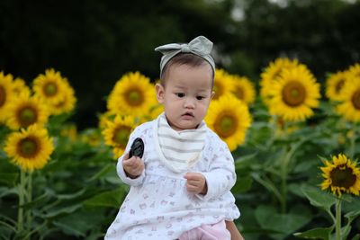 Cute girl against sunflower blooming at farm