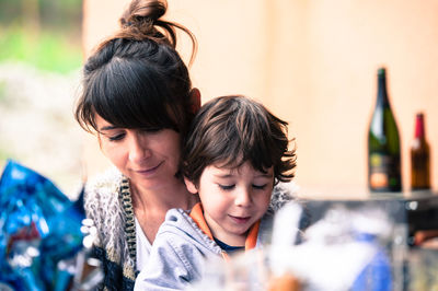 Smiling mother with cute son sitting at home