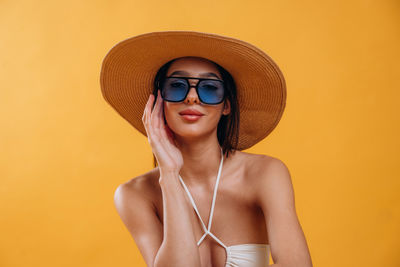 Portrait of woman wearing hat against yellow background