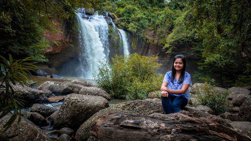 Young man sitting on rock in forest