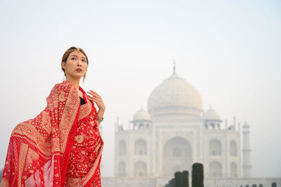 Young woman standing against historic building in india