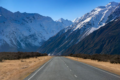 Road amidst snowcapped mountains against sky