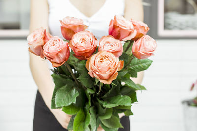 Midsection of woman holding rose bouquet