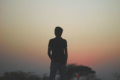 Silhouette man standing against orange sky