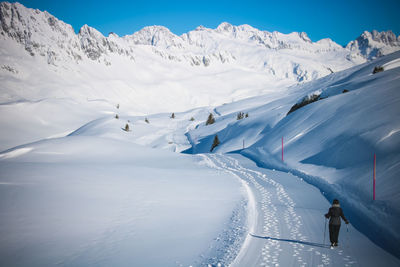 Rear view of woman walking on snow covered land during winter