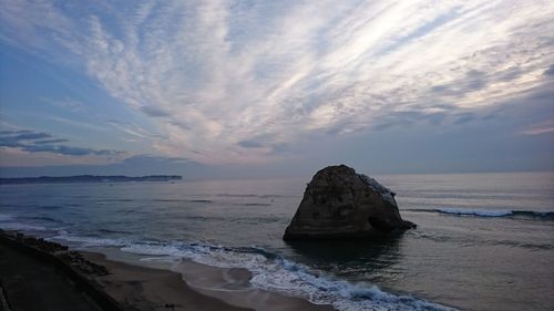 Rock formation in sea against sky during sunset