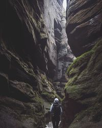 Rear view of woman standing on cliff against sky