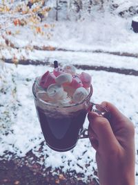 Cropped hand of woman holding hot chocolate in cup during winter