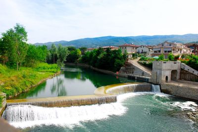 Scenic view of river amidst buildings against sky