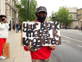 Portrait of man with text on street in city