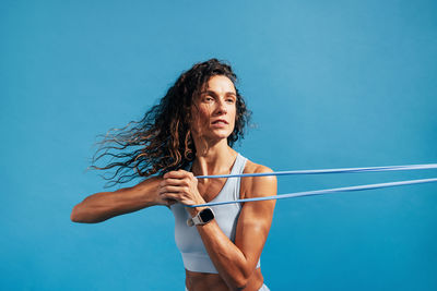 Close-up of woman exercising against blue background