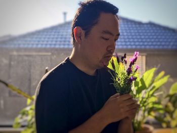 Close-up of young man looking at flower against blurred background