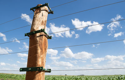 Low angle view of windmill on wooden pole against sky