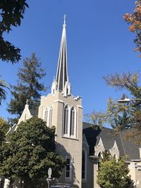 Low angle view of trees and building against sky