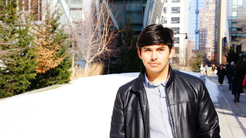 Portrait of man wearing leather jacket while standing in city