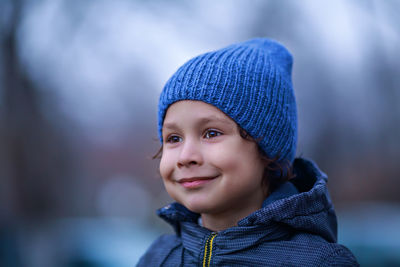 Close-up of smiling boy looking away during winter