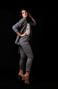 Portrait of smiling young woman standing against black background