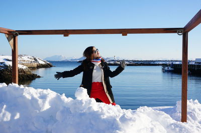 Young woman standing on snow against sky