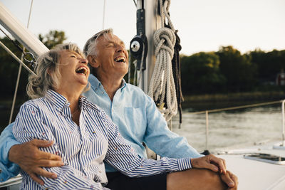 Cheerful couple laughing while spending leisure time in sailboat