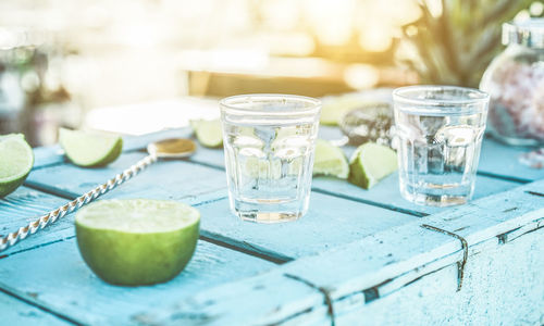 Close-up of limes and drink on table