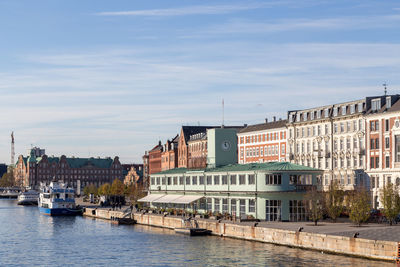 Buildings by river against sky