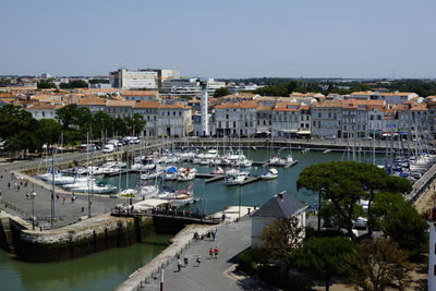 High angle view of boats moored at harbor against buildings in city