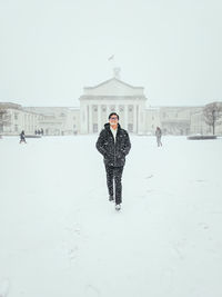 Man walking against buildings in city during winter