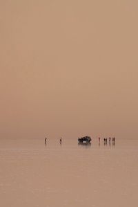 Silhouette people on beach against sky during sunset