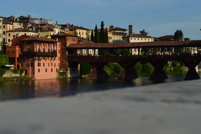 Bridge over river in city against sky