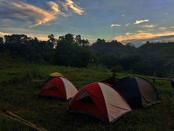 Tent on landscape against sky during sunset