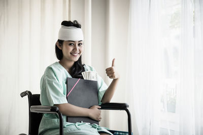 Woman with bandaged head and leg gesturing while sitting on wheelchair hospital