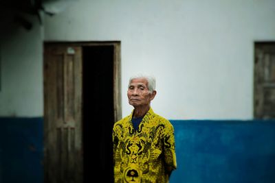 Portrait of senior man standing against wall