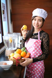 Portrait of smiling young woman holding fruits