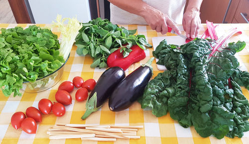 Midsection of woman cutting vegetable at table in kitchen