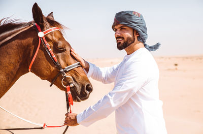 Man with horse in desert against sky