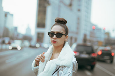 Portrait of woman in sunglasses against buildings