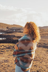 Rear view of woman standing on mountain against sky