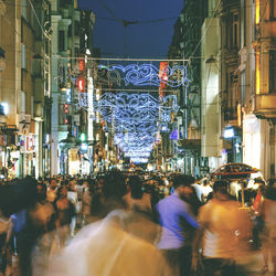 People on street amidst buildings in city at night